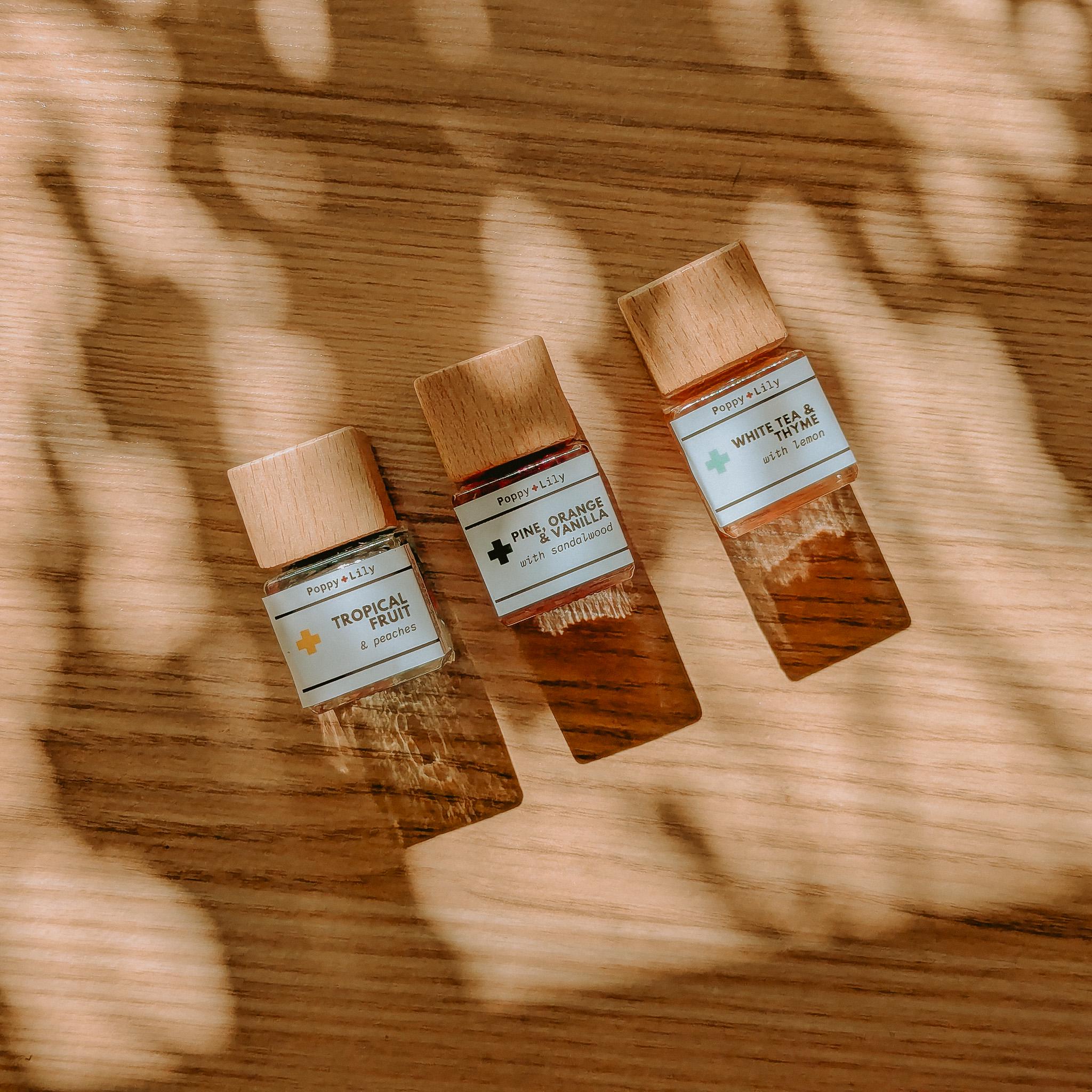 Three small bottles of diffusers with wooden caps on a wooden surface