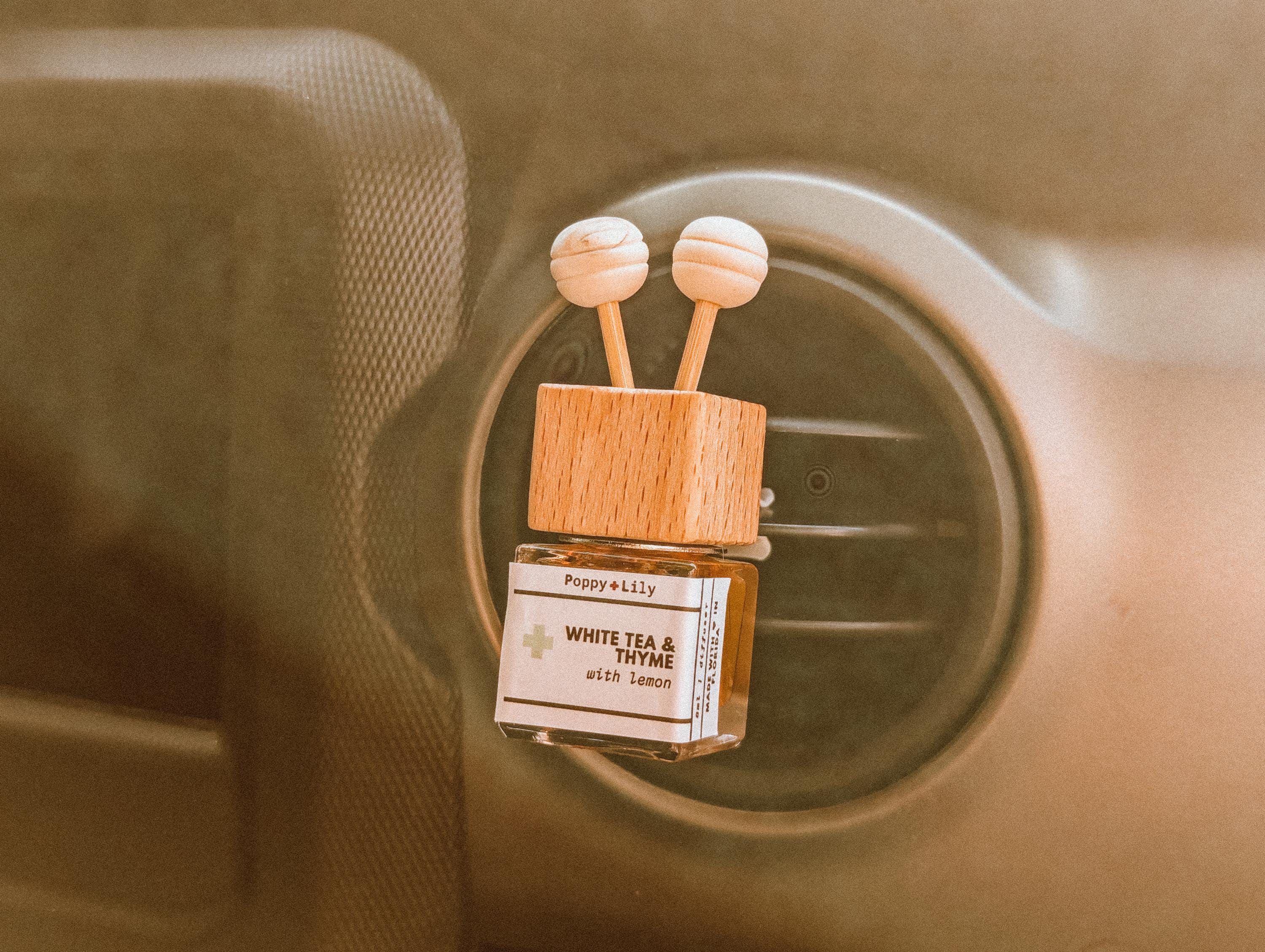 Car air freshener with wooden design and visible brand name on a car vent.