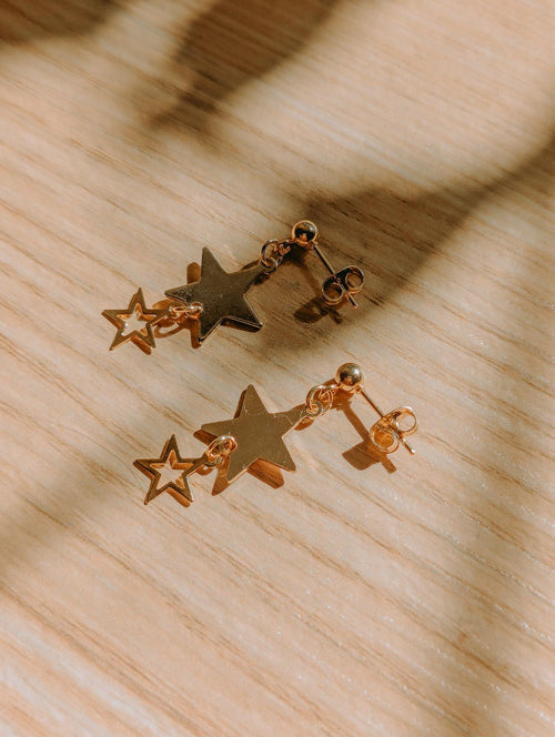 Pair of gold star-shaped earrings on a wooden surface