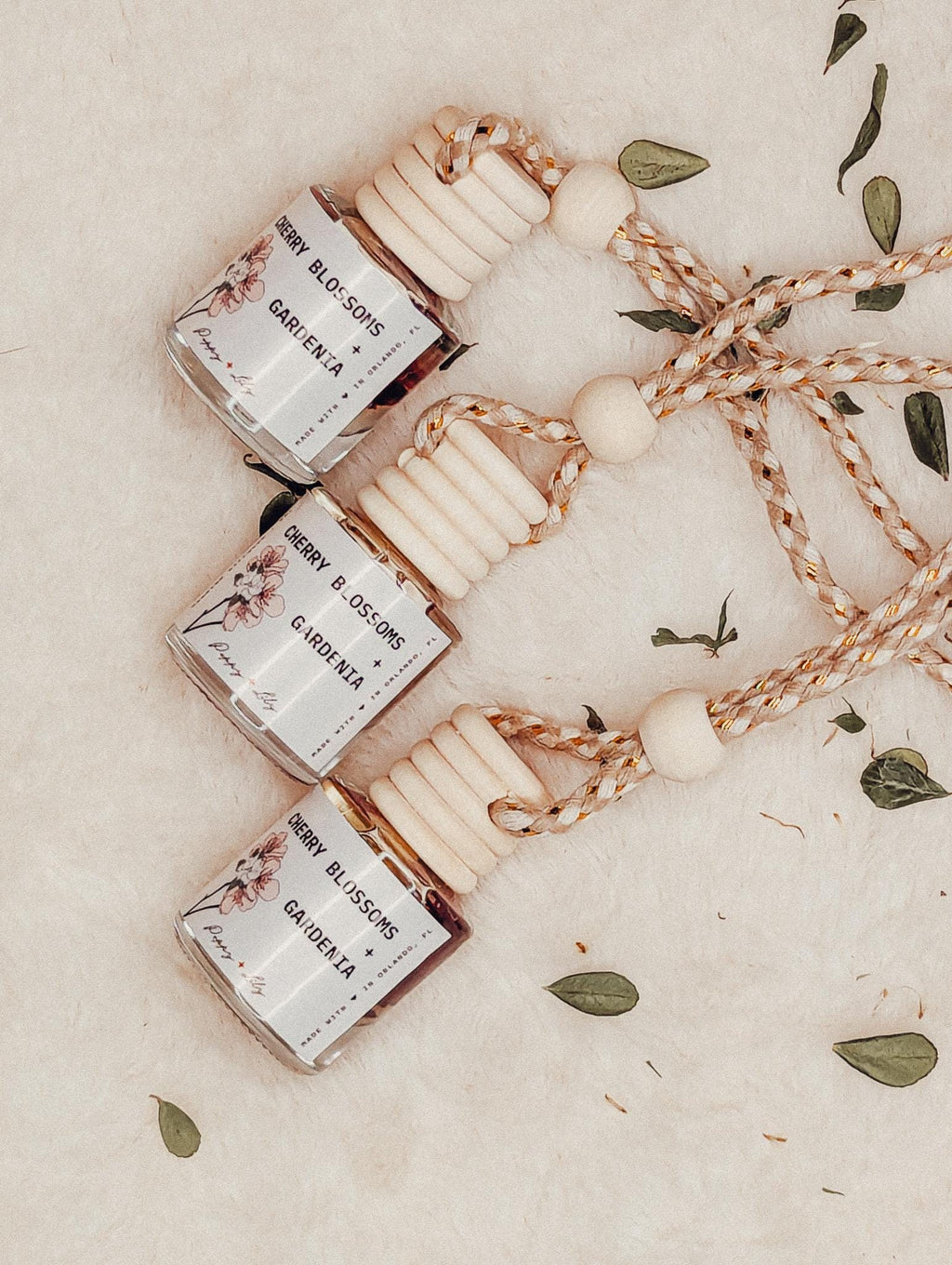 Three small bottles with floral labels on a beige surface with decorative elements.