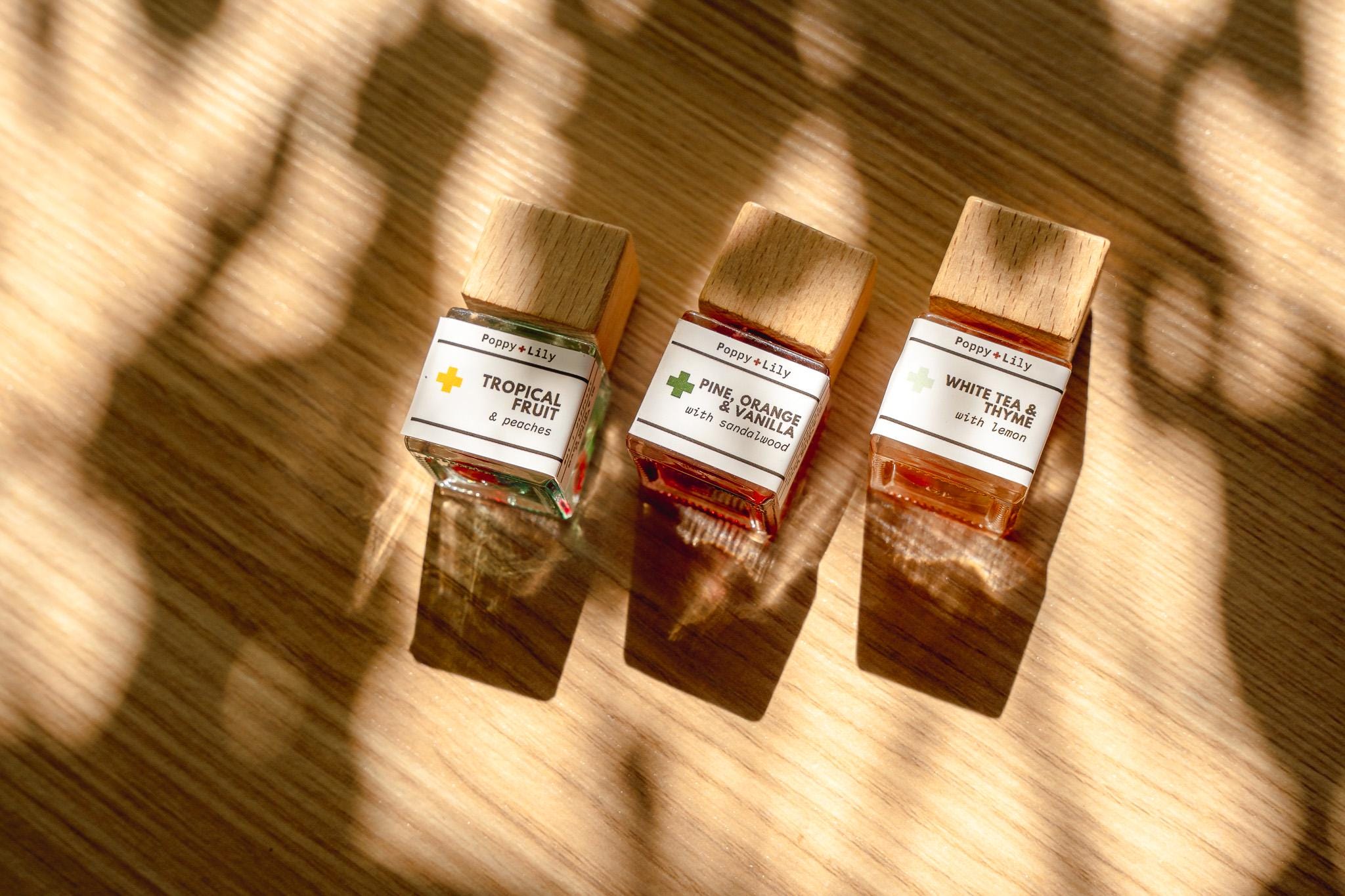 Three small bottles of perfume on a wooden surface with a warm glow.