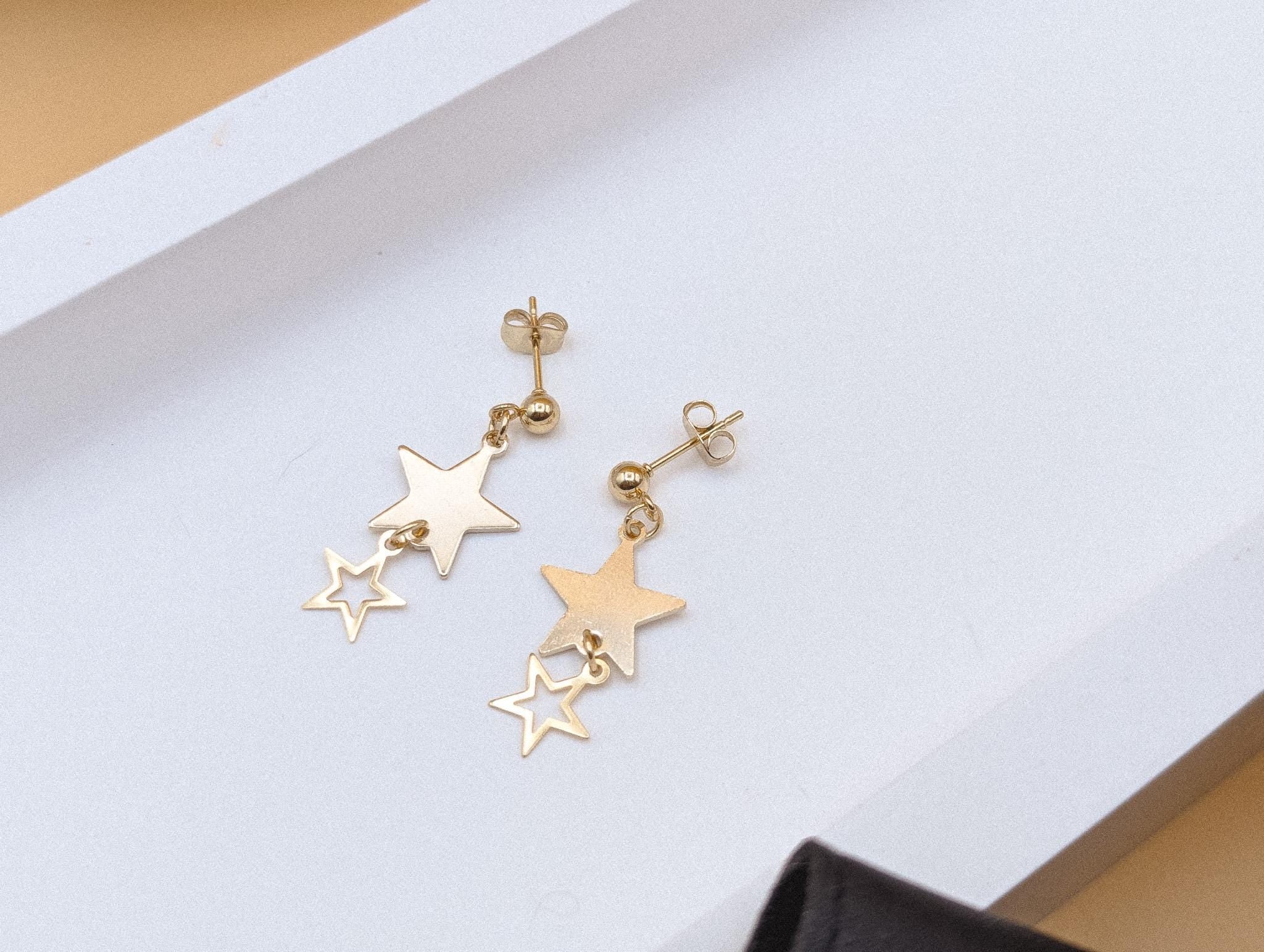 Gold star-shaped earrings on a light gray background